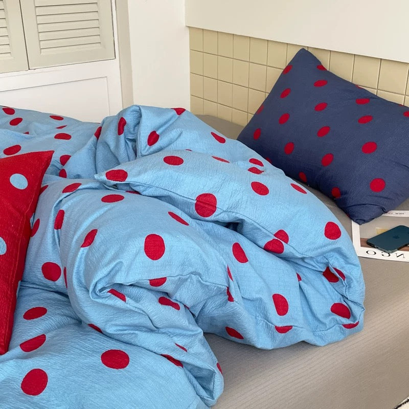 Blue polka dot bedding featuring bold red dots, perfect for teen girl bedrooms and modern dorm room decor.