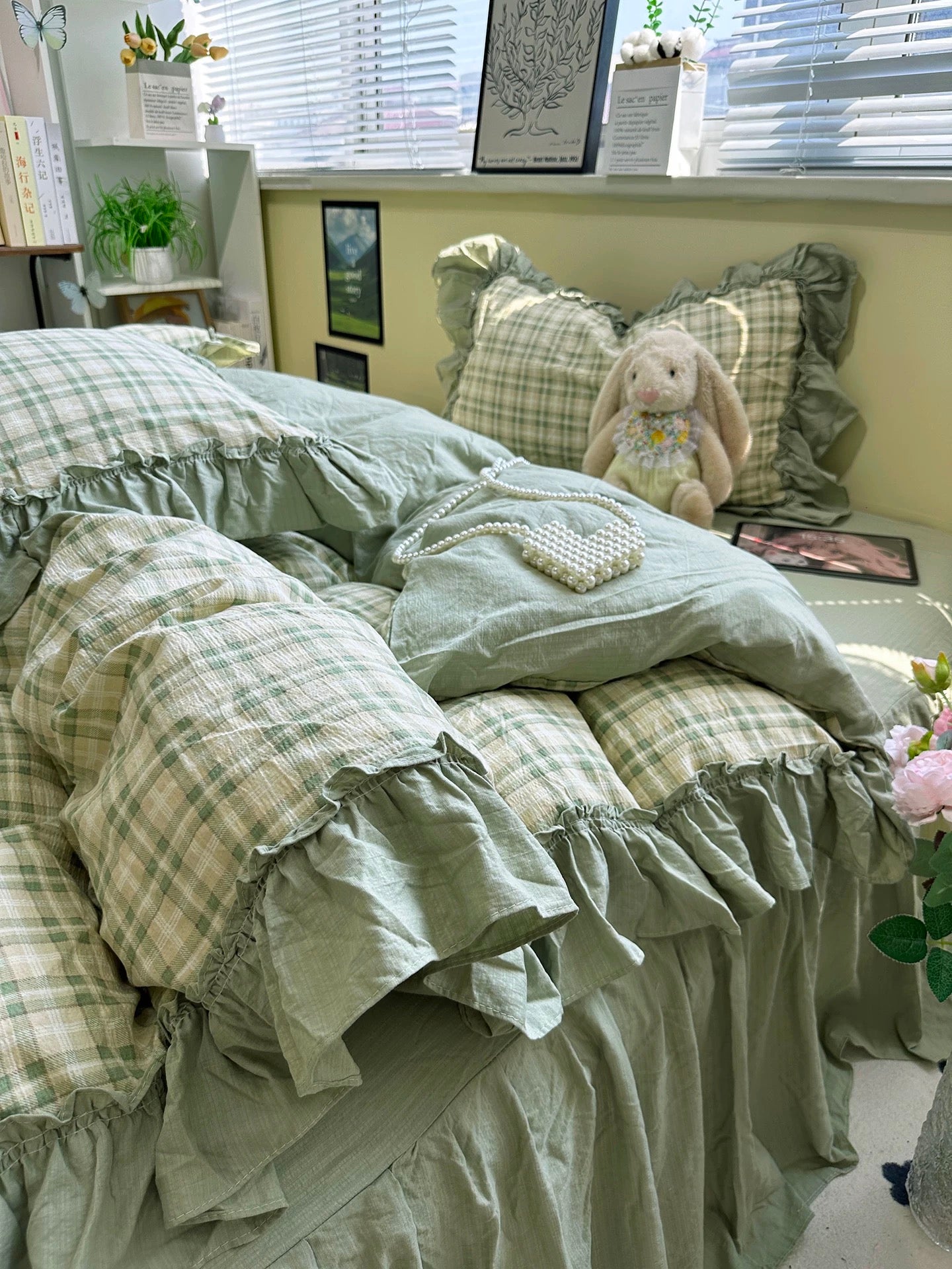 Bed with green plaid bedding and a plush bunny toy in a room with plants and decor.