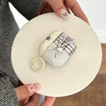 Small checkered bag with a ring held by a person on a white surface