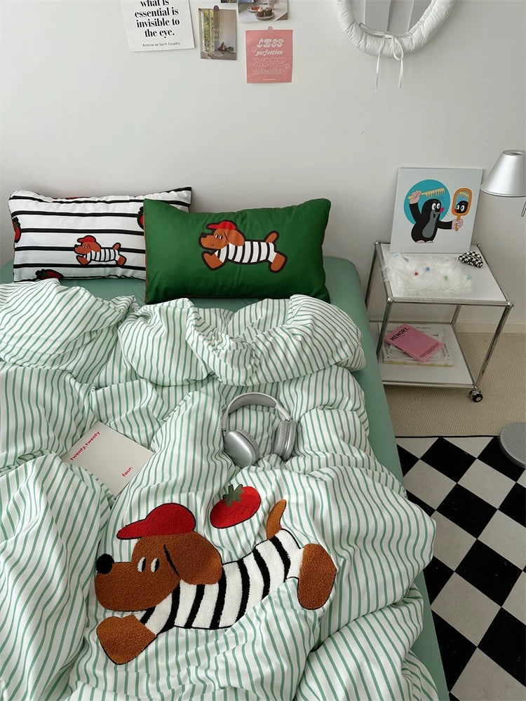 Bedding set with dog design on a bed in a room with a mirror and small table.