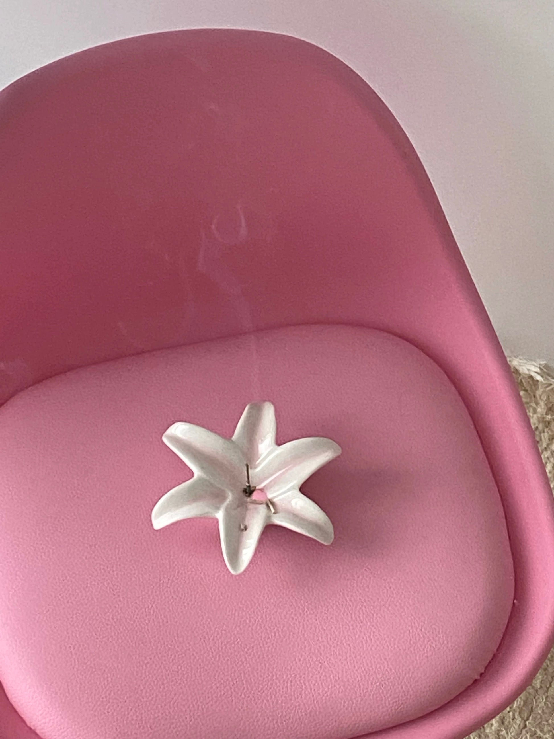 White ceramic flower on a pink cushioned chair