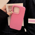 Pink phone case held by a person with a blurred background