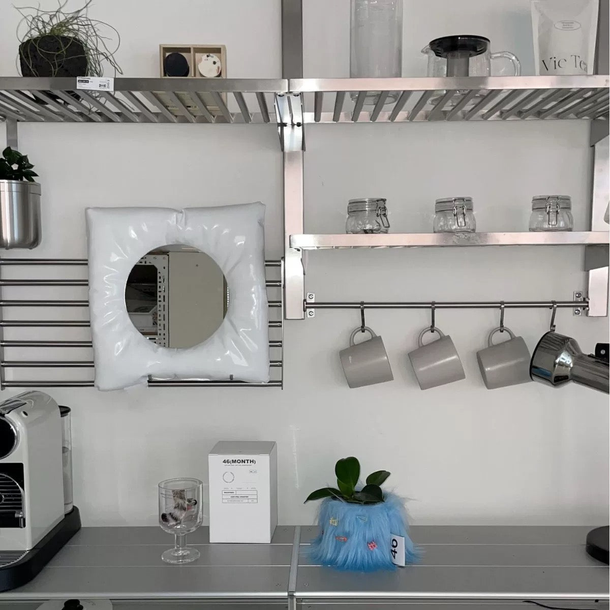 Kitchen with metal shelves, hanging mugs, and a white appliance.
