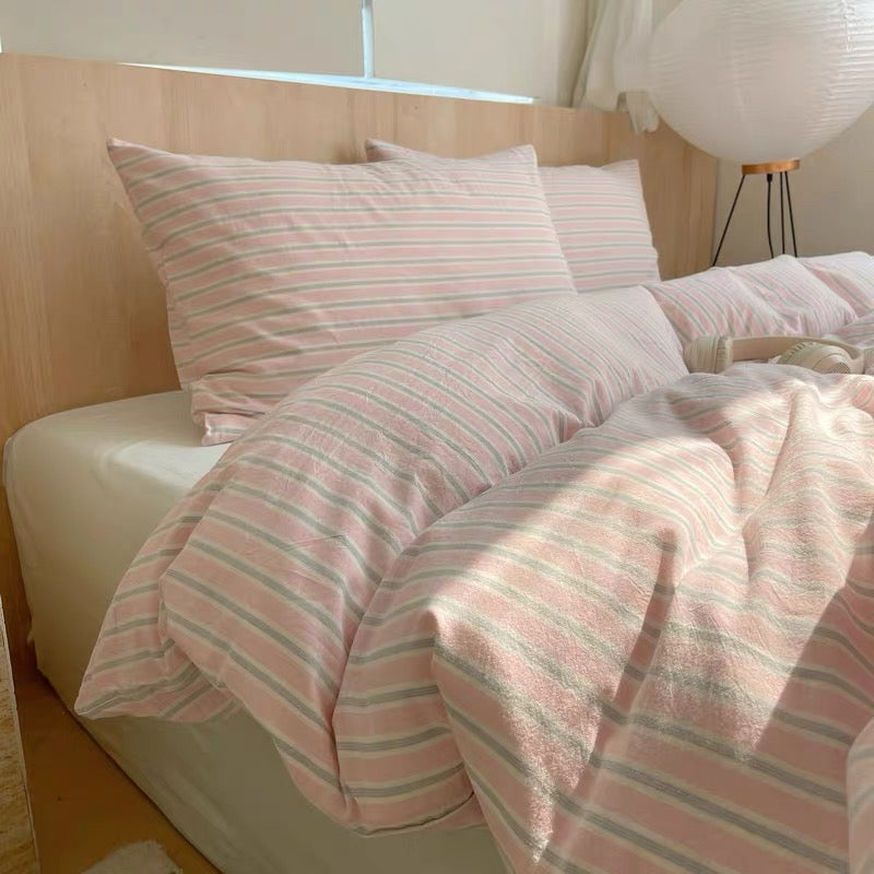 Bed with pink and gray striped bedding in a bright room