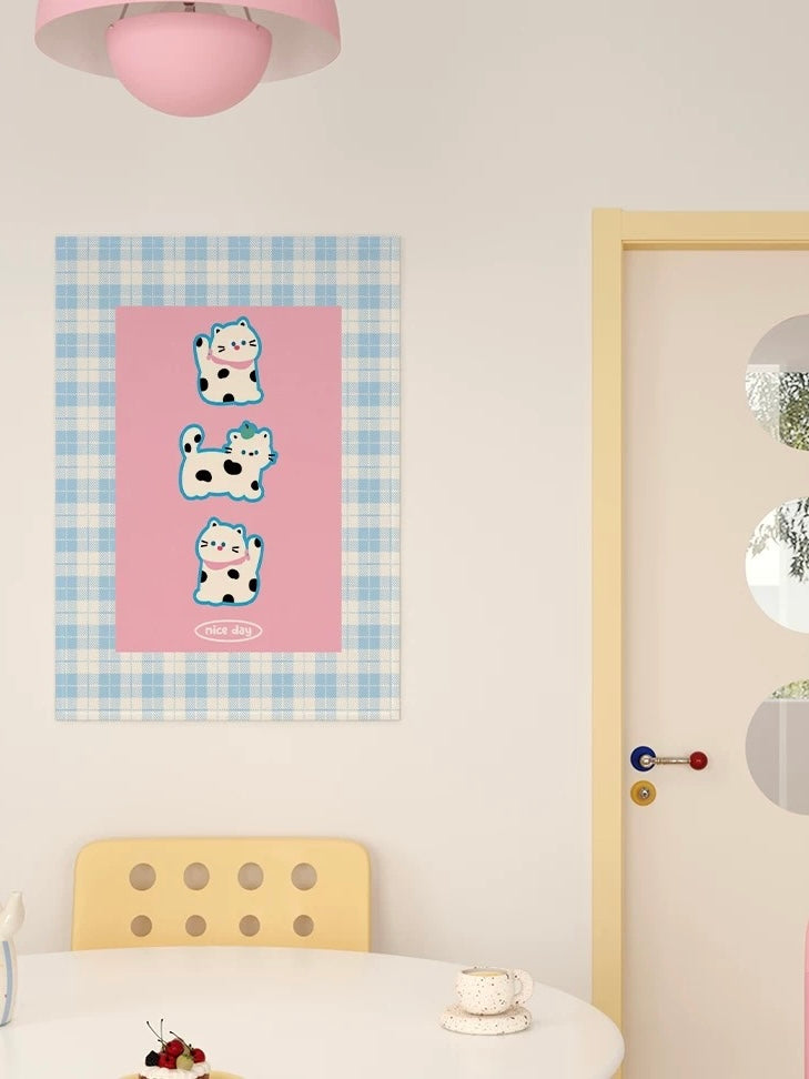 An animal tapestry with three spotted cats on a pink panel and a blue plaid border hangs above a table.