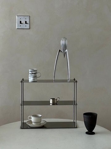 Modern glass shelf with decorative items against a plain wall.