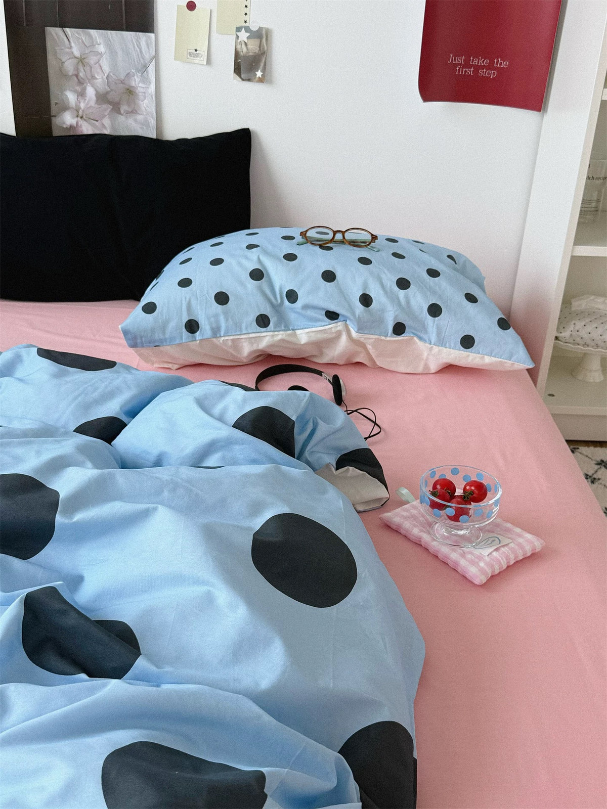 A small dotted blue pillowcase sits in front of a black pillow above the large dotted blue cover.
