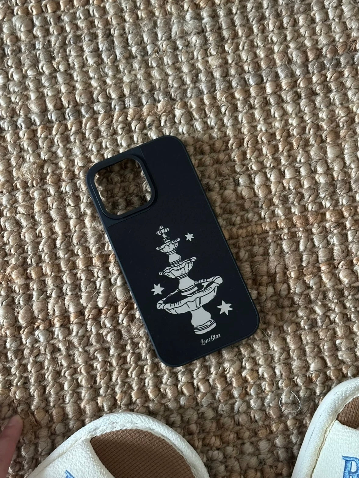 A black star phone case viewed from above at an angle, with the pale fountain centered on the back.