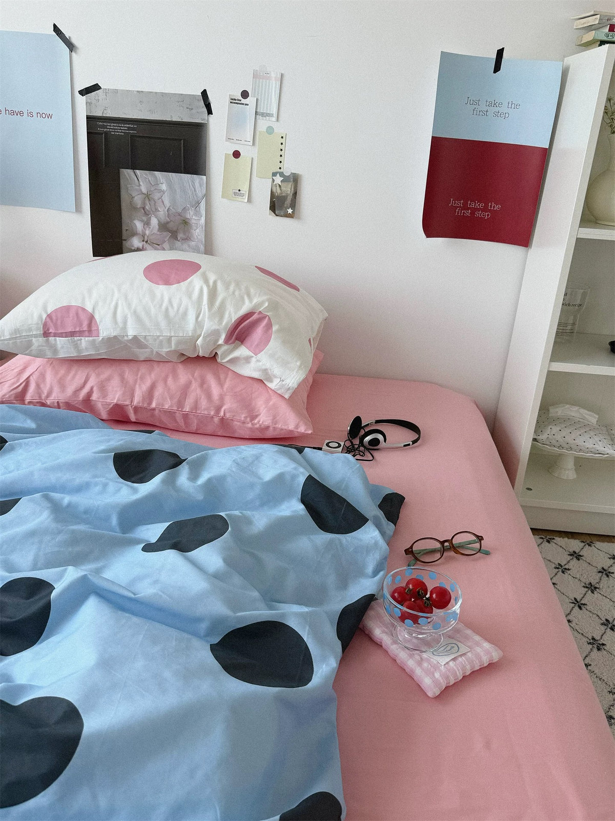 A plain baby pink pillowcase and a cream pillowcase with pink dots sit above the blue cover and pink sheet.