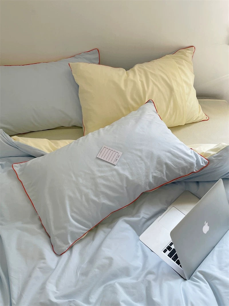 Laptop on a bed with light-colored pillows and bedding
