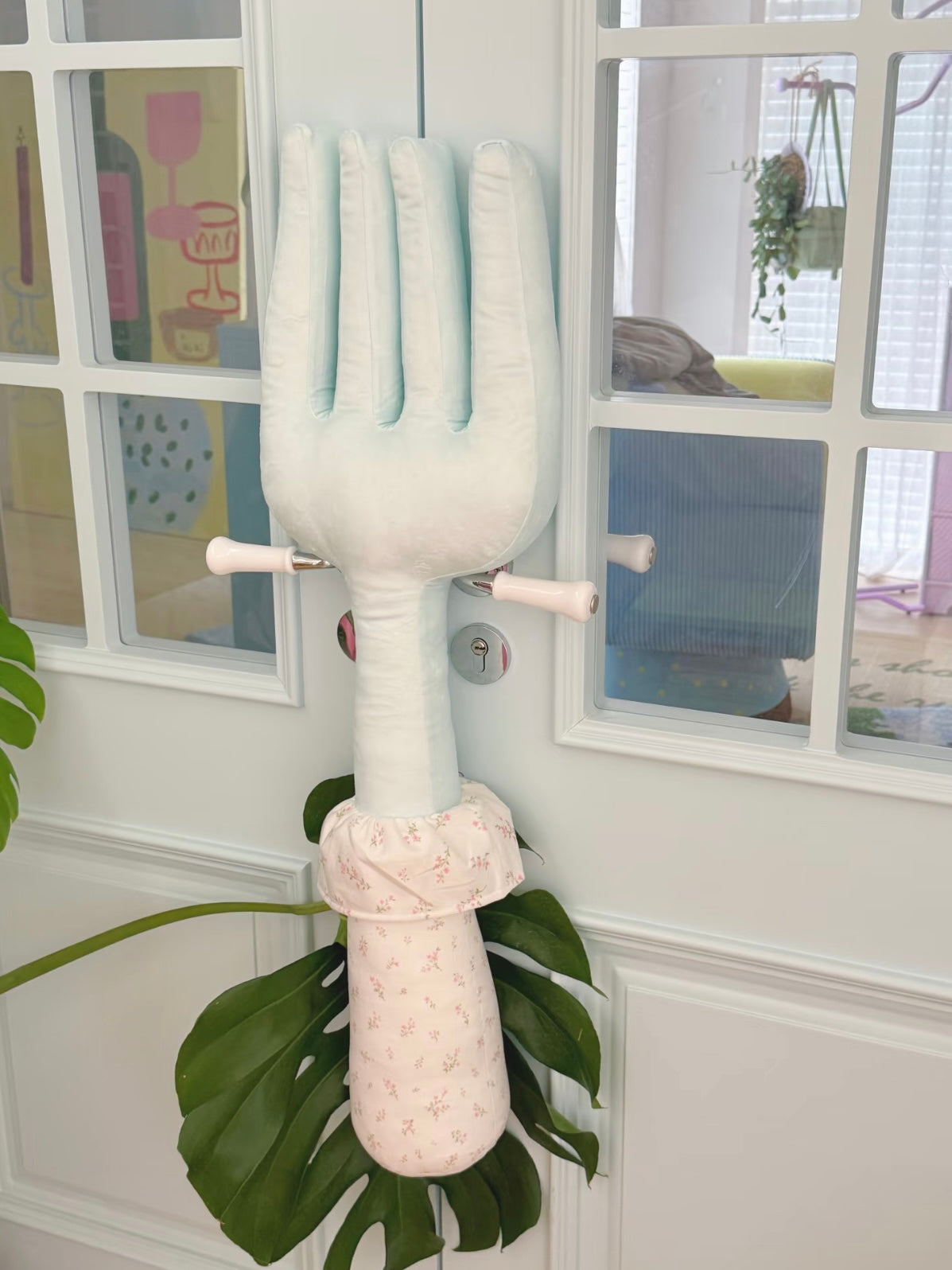 A pale blue fork plush pillow stands upright, showing long tines and a light floral handle with a gathered cuff.