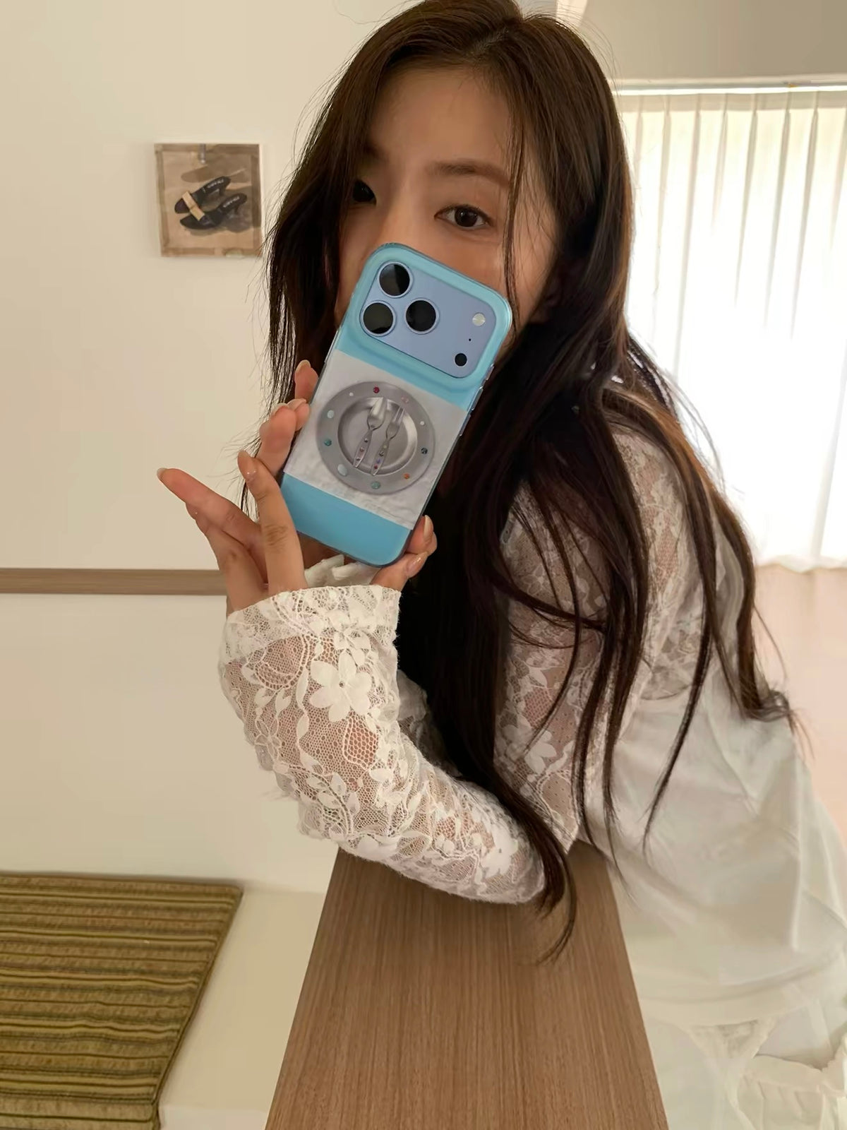 A blue matte phone case held up for a mirror selfie, with the illustrated plate and cutlery facing out.