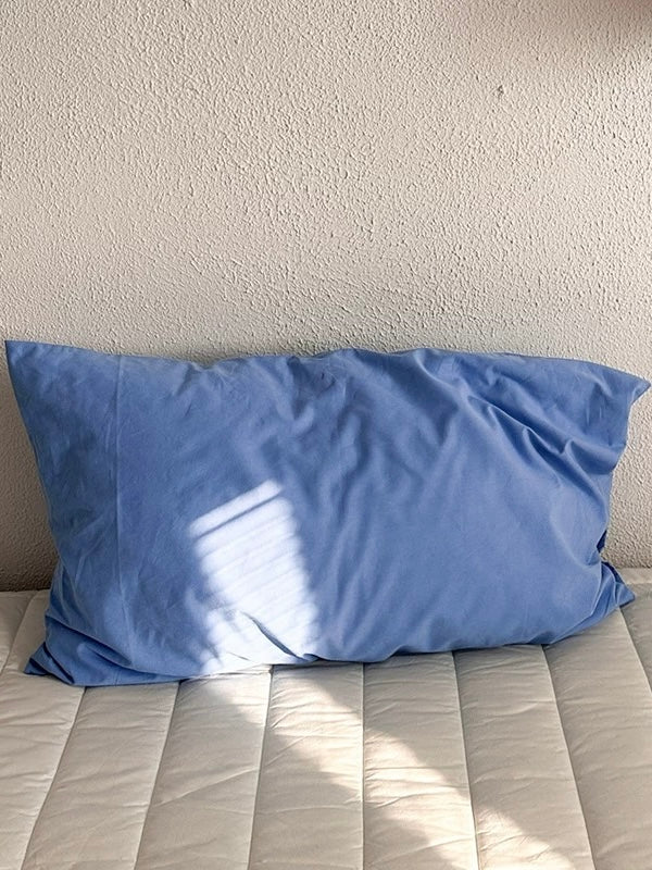 A blue pillowcase in solid cotton with visible fabric creases.