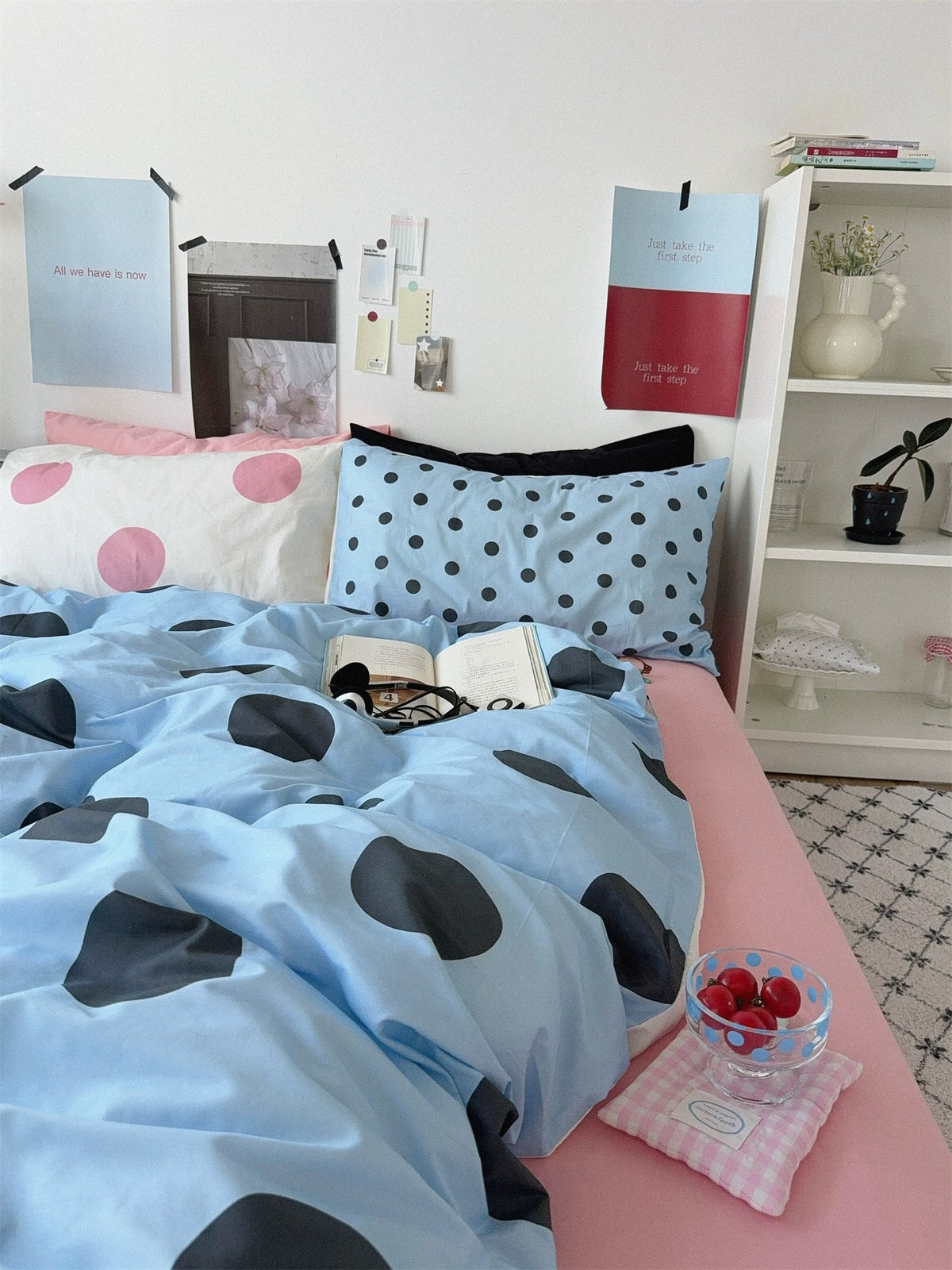 An angled view shows the blue dotted cover turned down over a pink sheet with dotted pillowcases at the head.