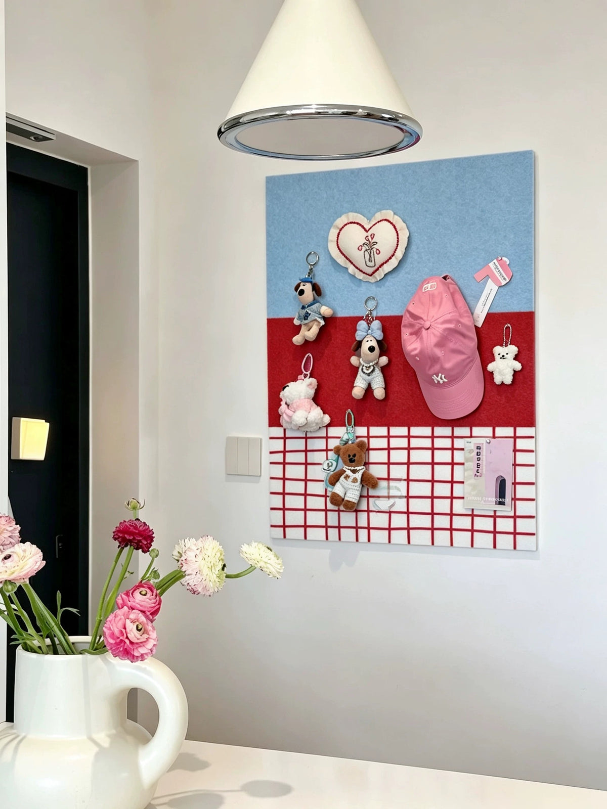 Blue and red felt pin board styled in a bright room above a tabletop with flowers