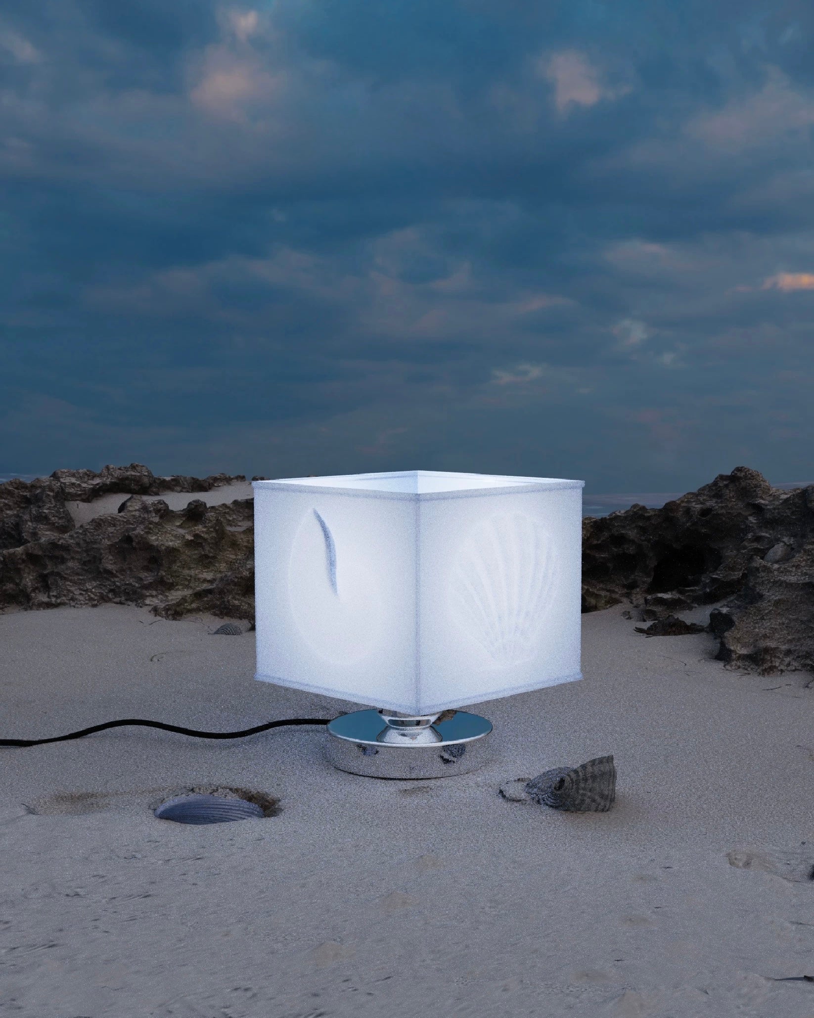 White cube-shaped lamp on a sandy surface with a cloudy sky background