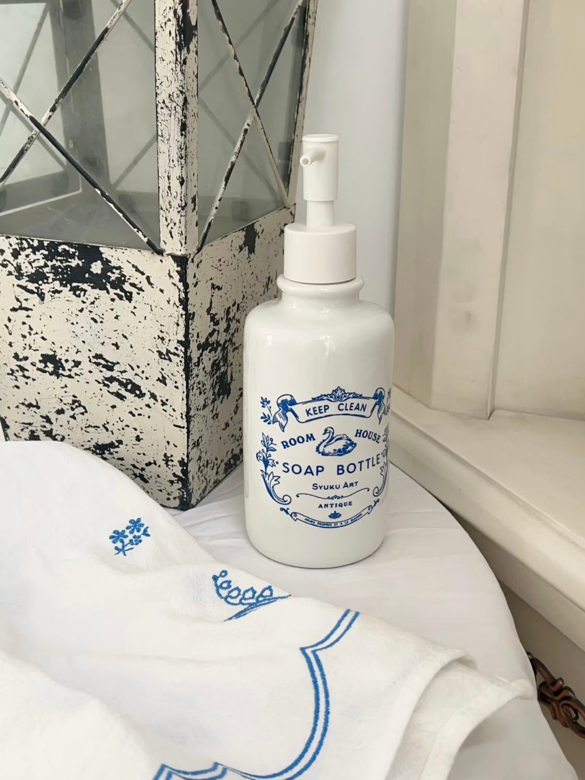 Blue soap dispenser stands upright with a white pump and swan artwork centered on the front of the bottle.