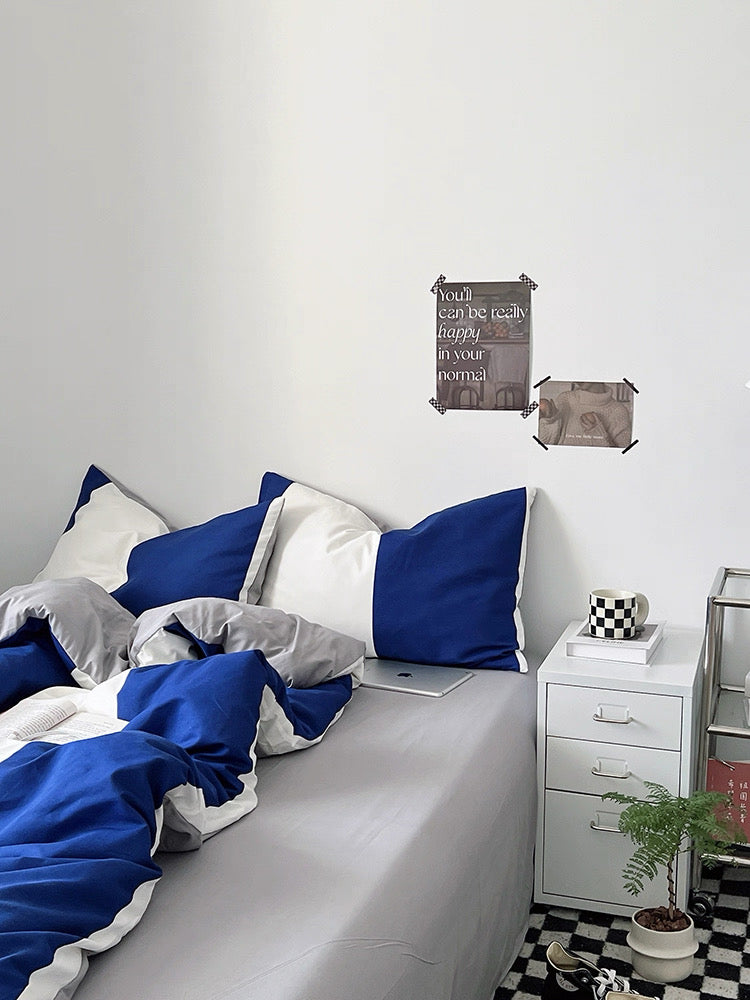 Bedroom with blue and white bedding, nightstand, and decorative items.