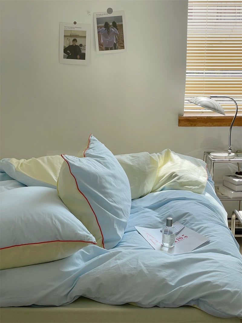 Bedroom with light blue bedding and a window with blinds.