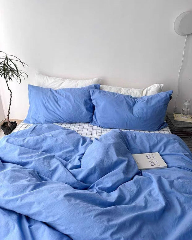 Blue bedding set on a bed with white pillows against a light gray wall.