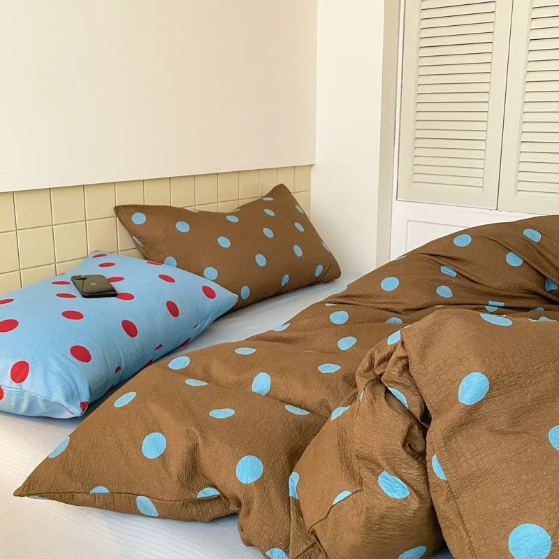 Brown polka dot bedding set with light blue dots styled in cozy preppy dorm room