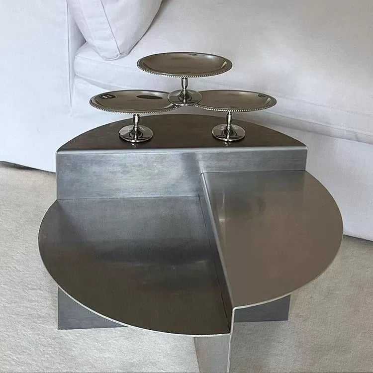 Stainless steel round coffee table showcasing elevated platform for books candles coffee and decorative accessories beautifully arranged.