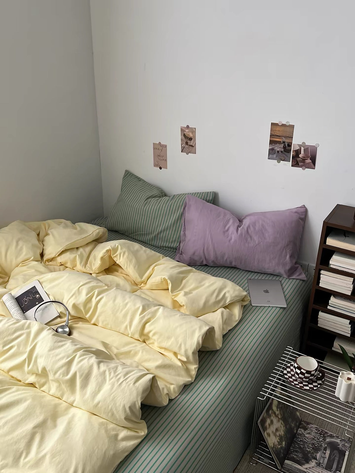 Butter yellow duvet cover layered over a sage striped flat sheet with lilac and green pillows