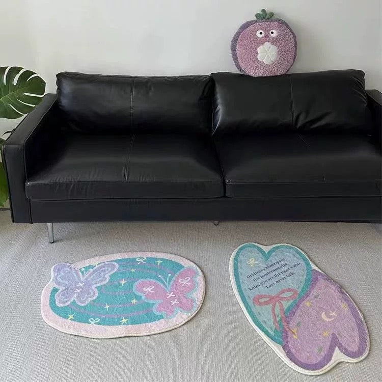 Pastel butterfly and heart bath mats arranged on a light floor in front of a black sofa