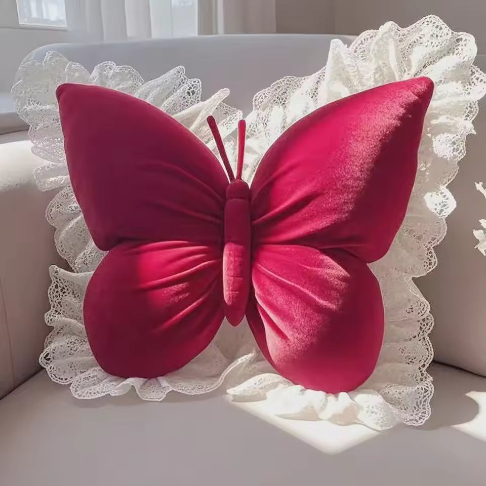 Red butterfly-shaped pillow on a white lace background