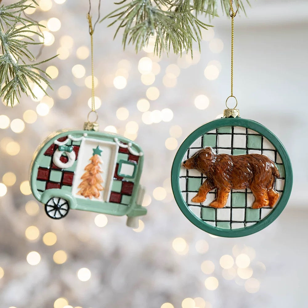Camper ornaments include a checked tree trailer, shown hanging beside a round brown bear ornament.