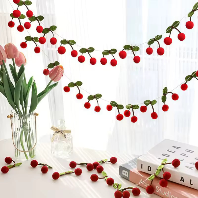 Decorative red berry garland on a white surface with books and flowers.