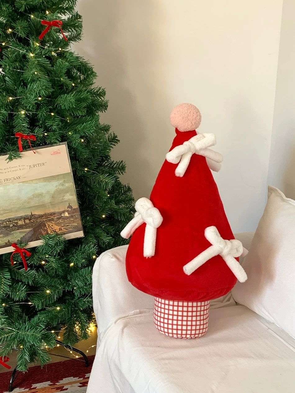 Christmas tree pillow with plush white bows styled beside a Christmas tree