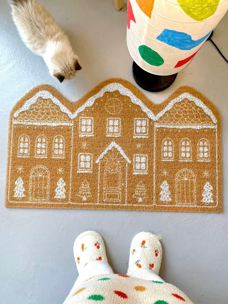 Cinnamon Christmas entryway mat with gingerbread house design and white slippers