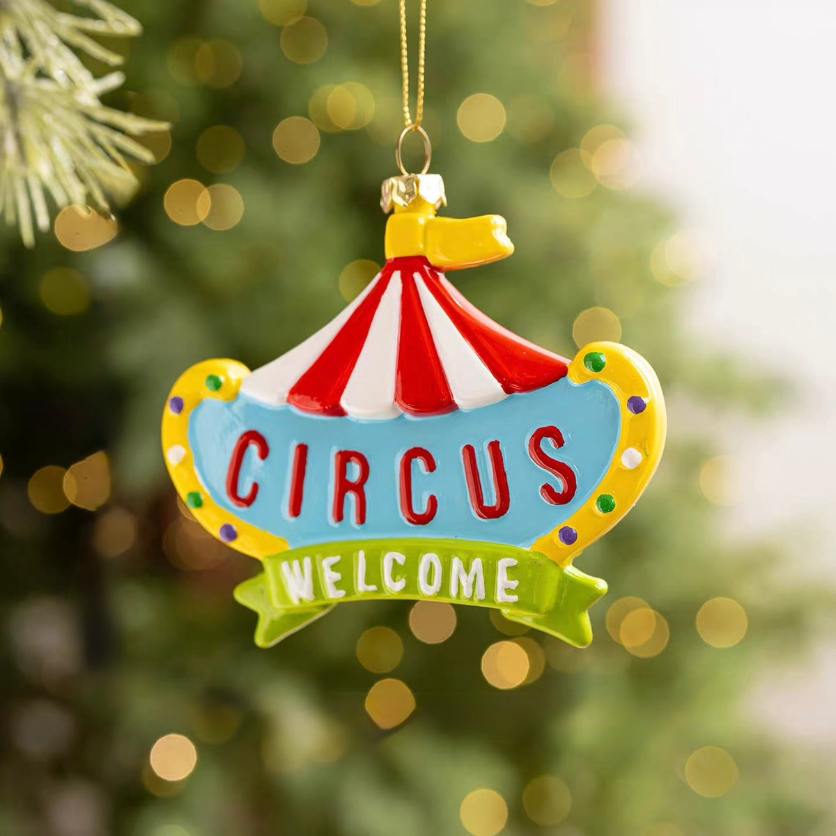 A circus sign ornament has red lettering, a red and white striped roof and a green Welcome banner.