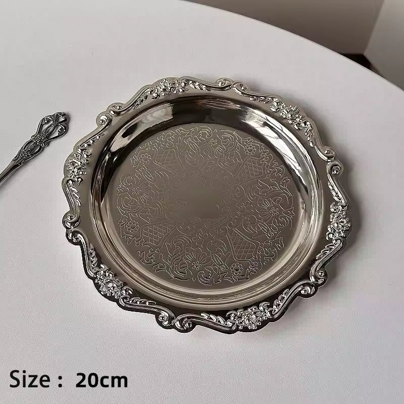 Silver decorative tray with intricate patterns on a white surface
