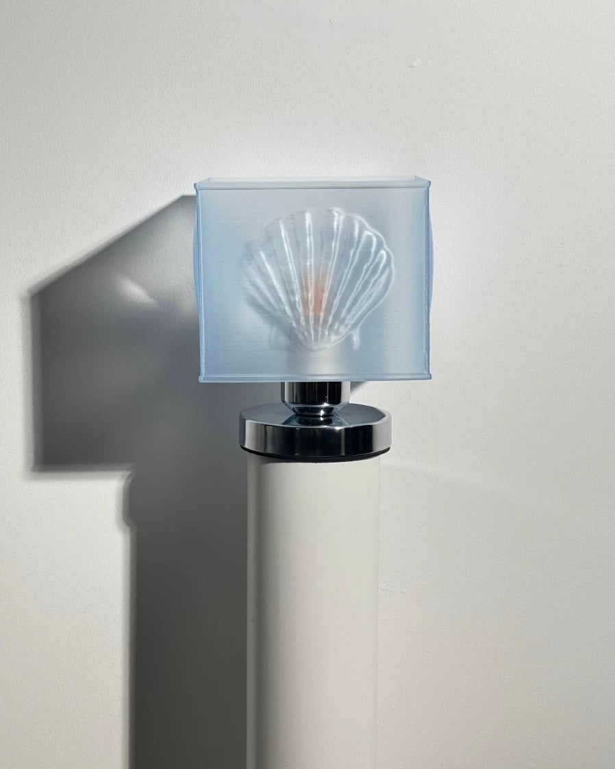 Modern wall lamp with a shell-shaped glass shade on a neutral background