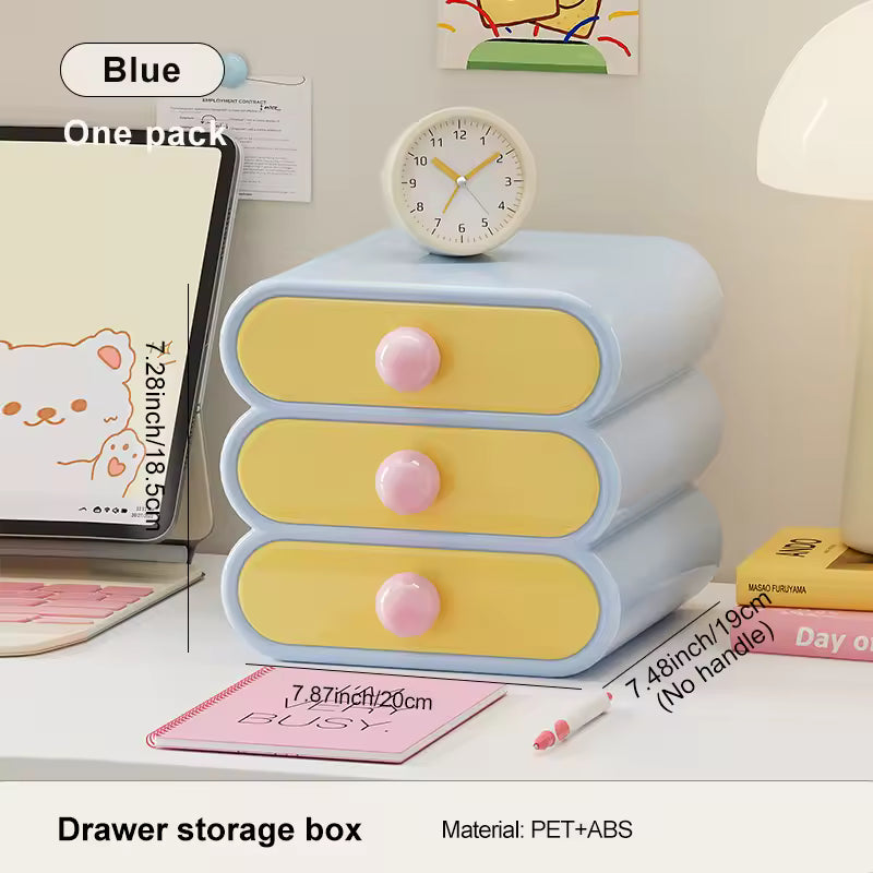 Three-layered drawer storage box with pink knobs on a desk, featuring a clock on top.