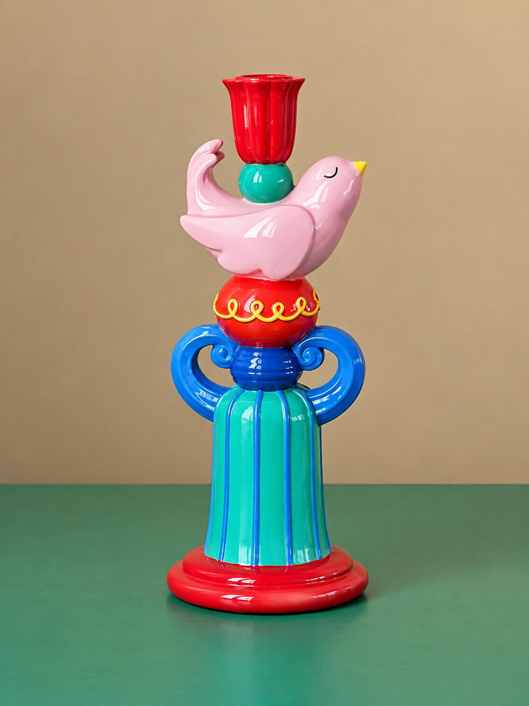 Pink and blue bird candle holders with lit taper candles styled together on a mirrored console.