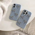 Two blue phone cases with bow designs on a white surface.