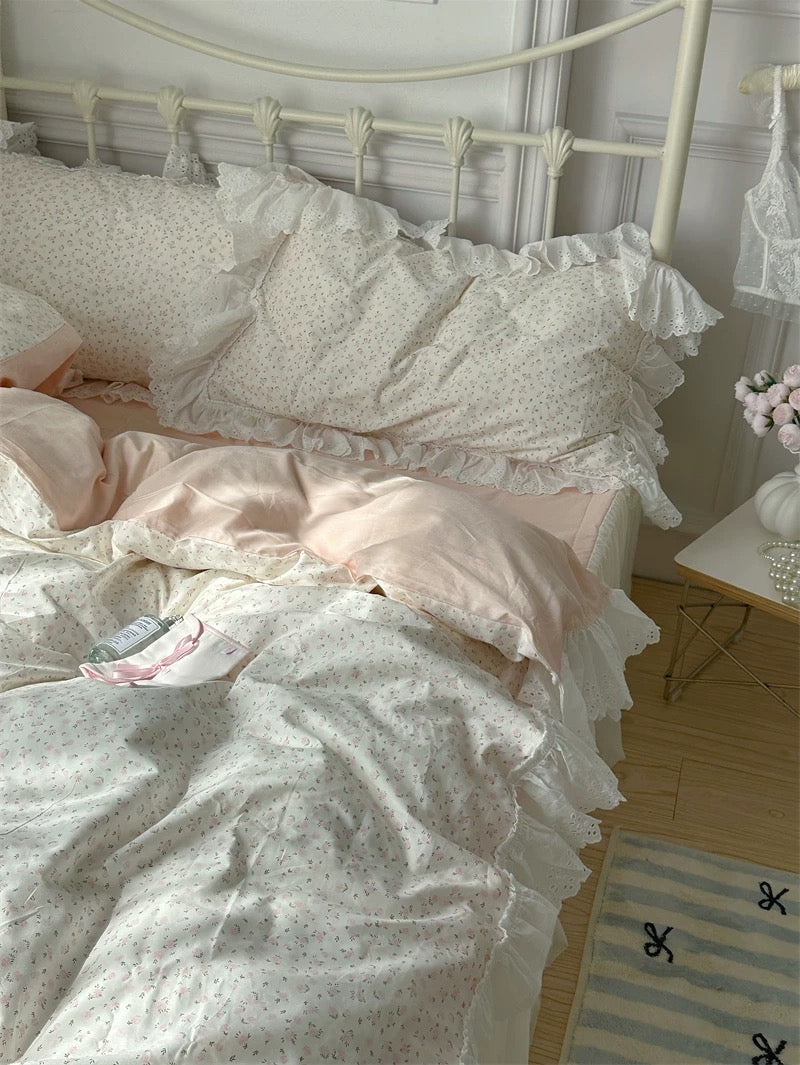Bed with ruffled bedding and pillows in a softly lit room.