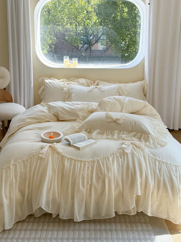 Neatly made bed with white bedding in a room with a window view of greenery.