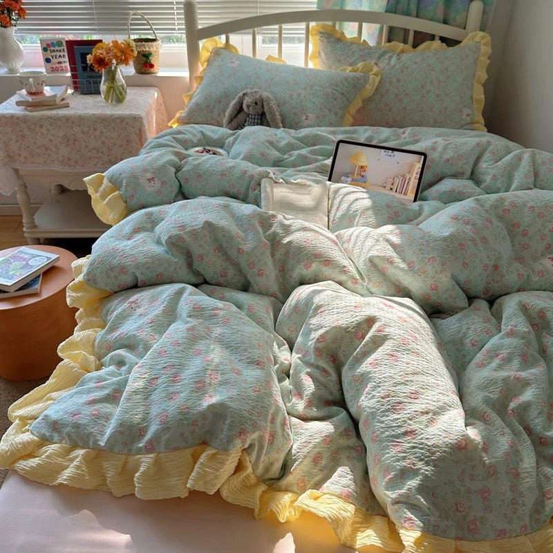 Pink and yellow ruffle pillowcase featuring an embroidered bunny accent on a floral bedding set
