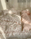 Close-up of pink embroidered flowers and lace trim on cotton duvet cover.