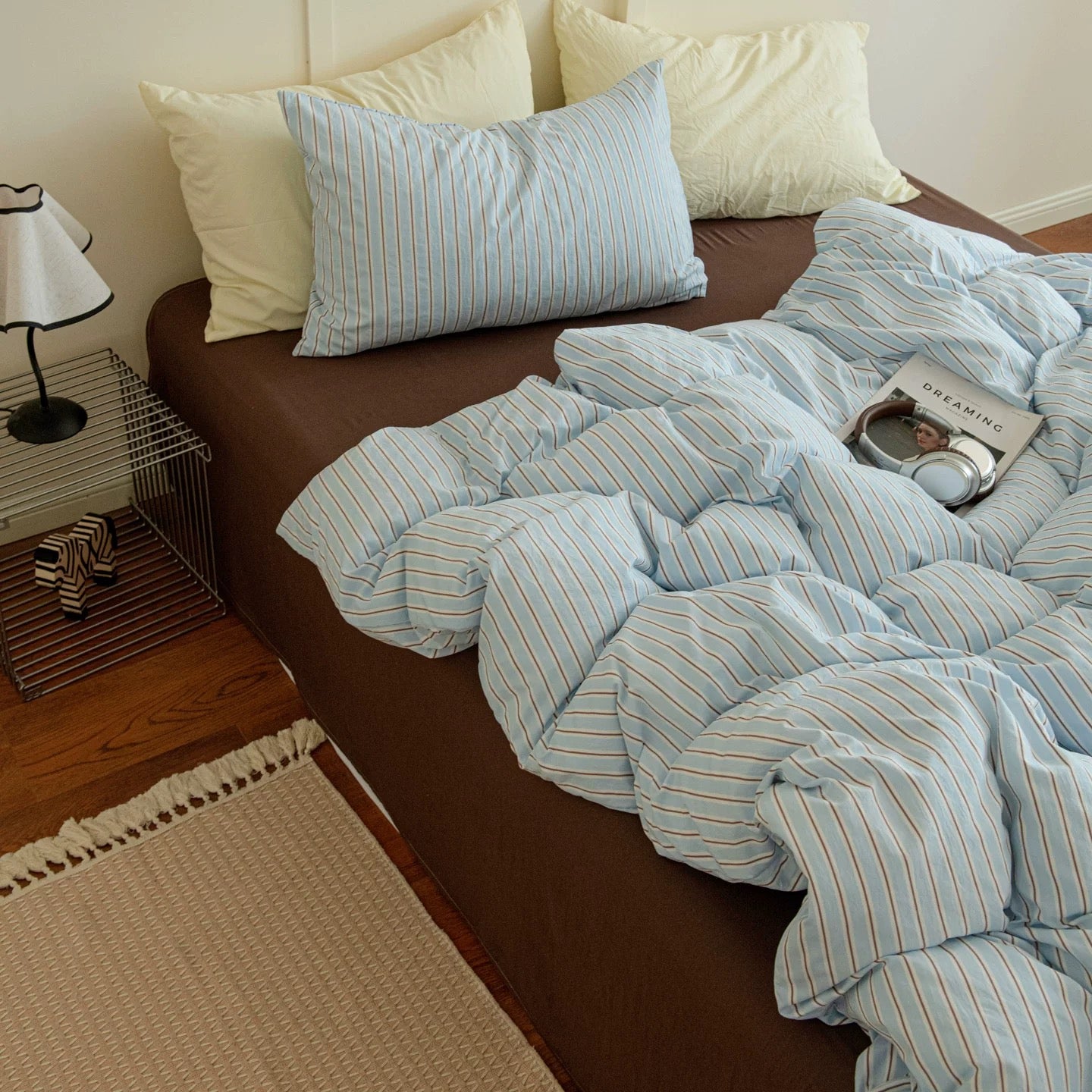 Bed with brown headboard and blue striped bedding in a bedroom setting.