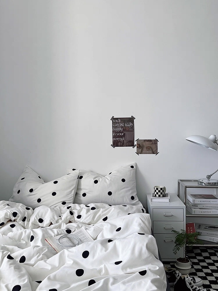 Bedroom with polka dot bedding, nightstands, and wall art.