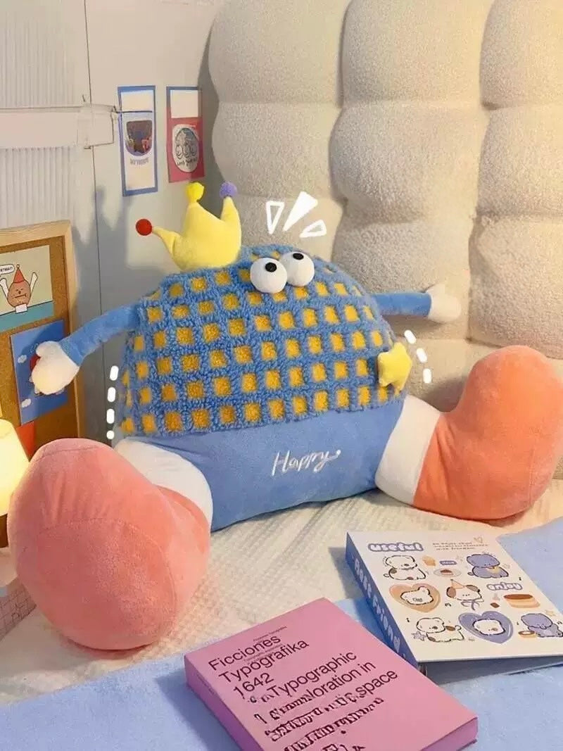 Plush toy with cartoon face on a bed next to books