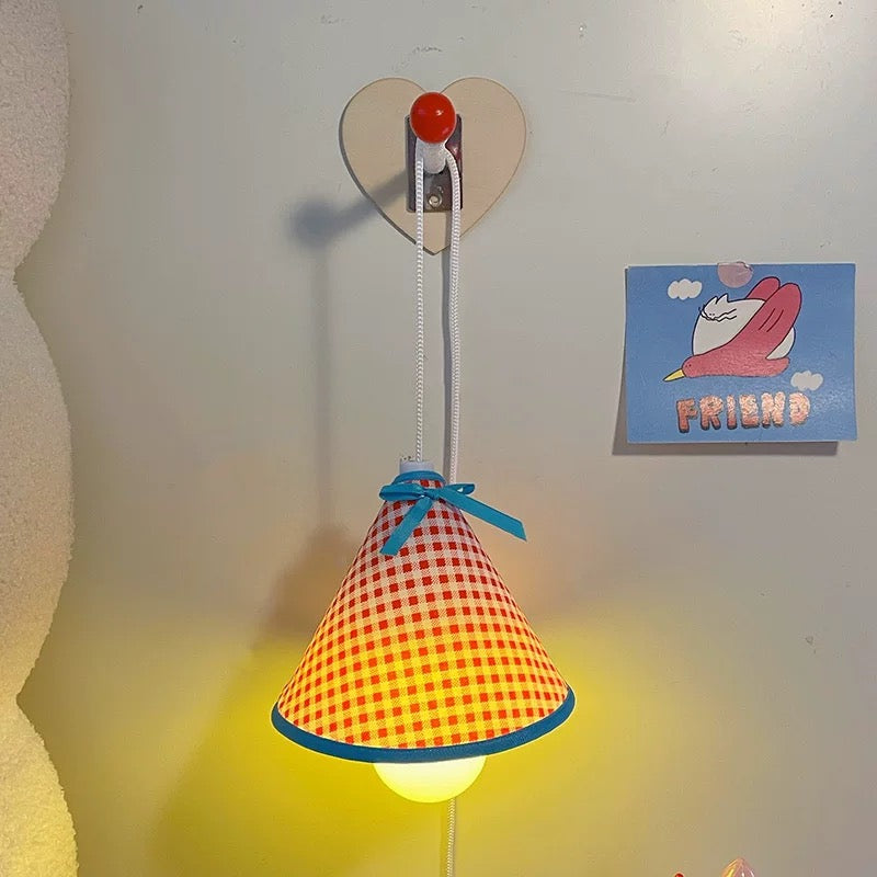 Colorful checkered lamp with a heart-shaped wall hook on a light-colored wall.