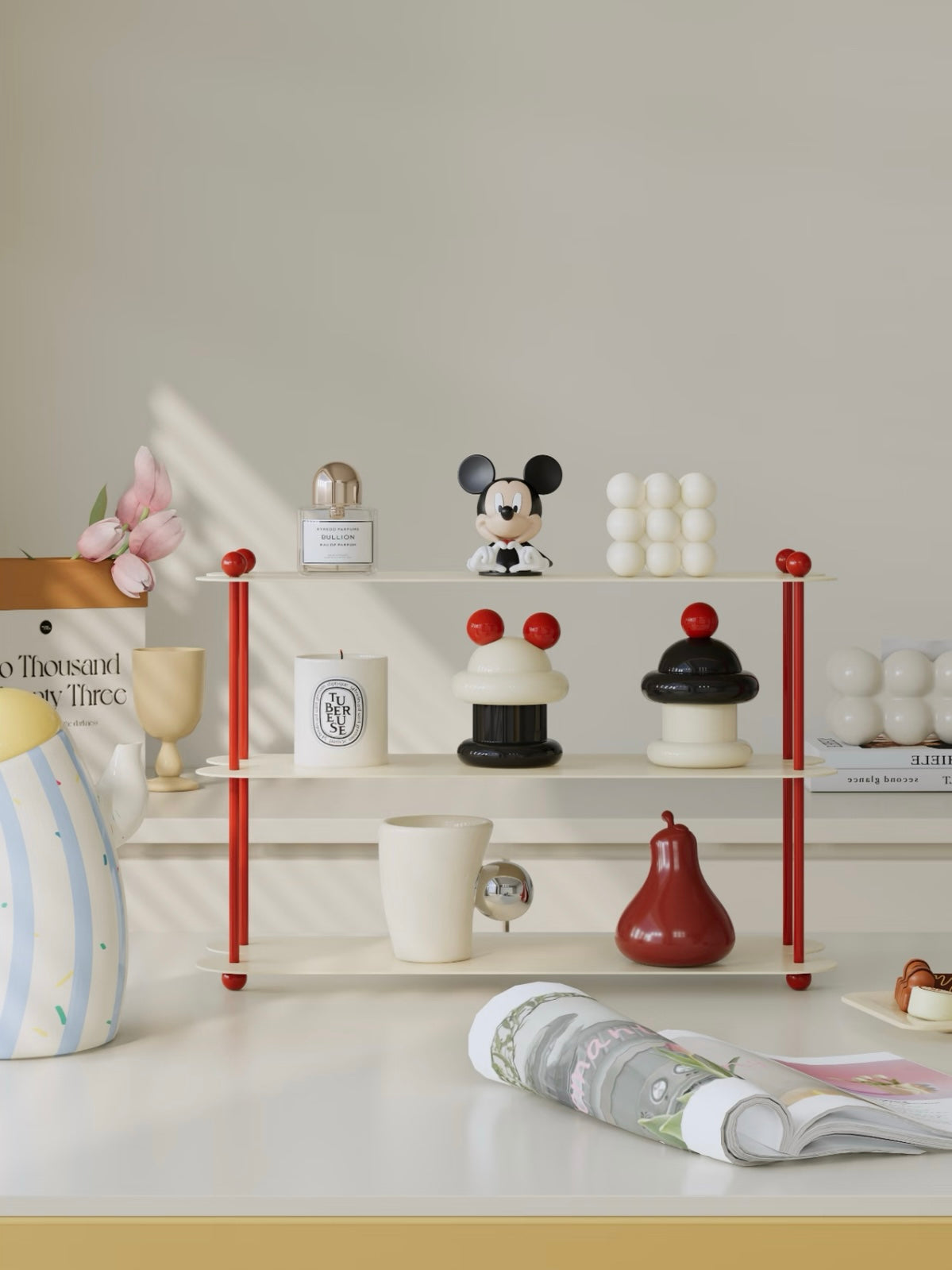 A cream display shelf with red posts is shown from the front with a white mug and red pear shaped object.