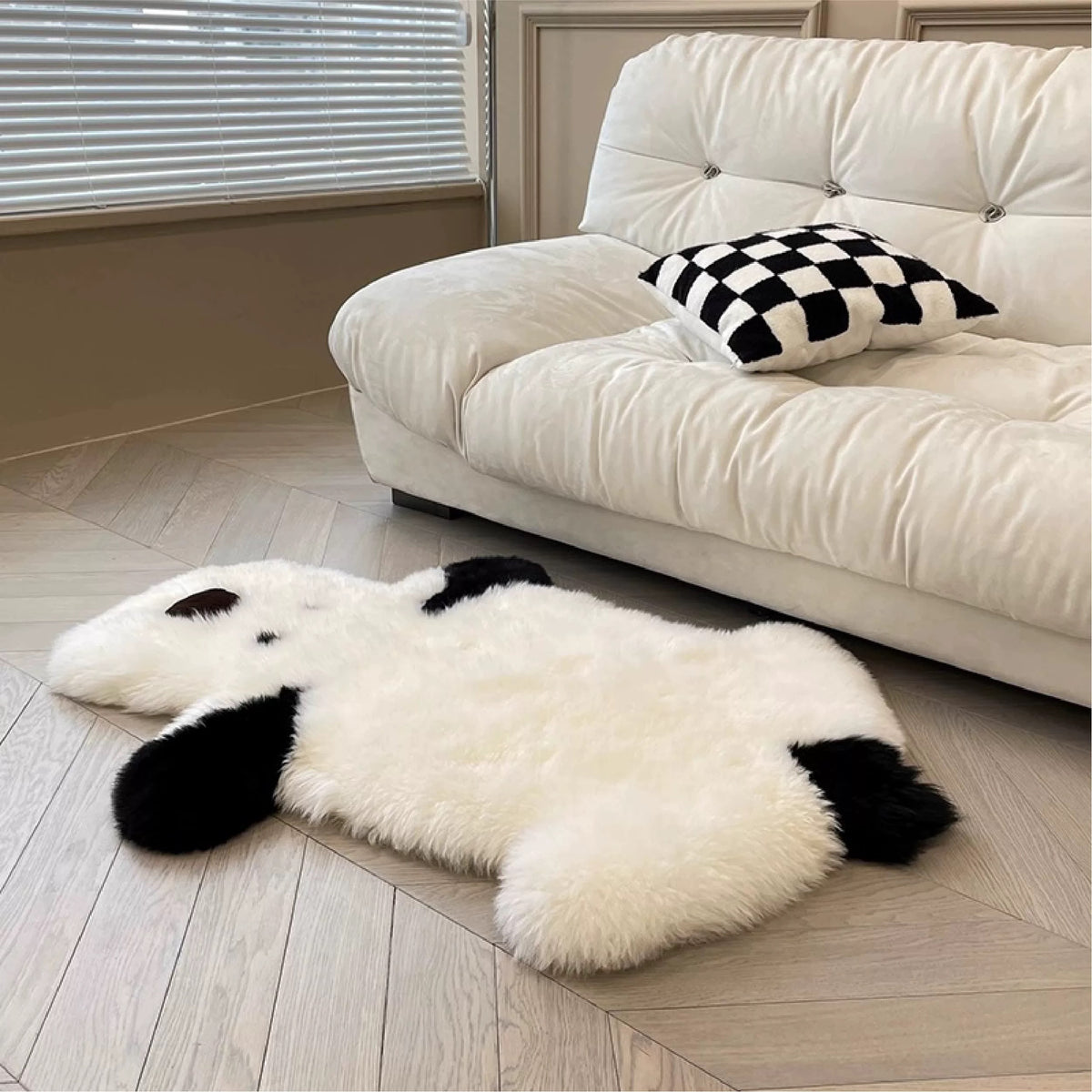 A cream dog rug lies in front of a white sofa, with the full body and black ears visible across the floor.
