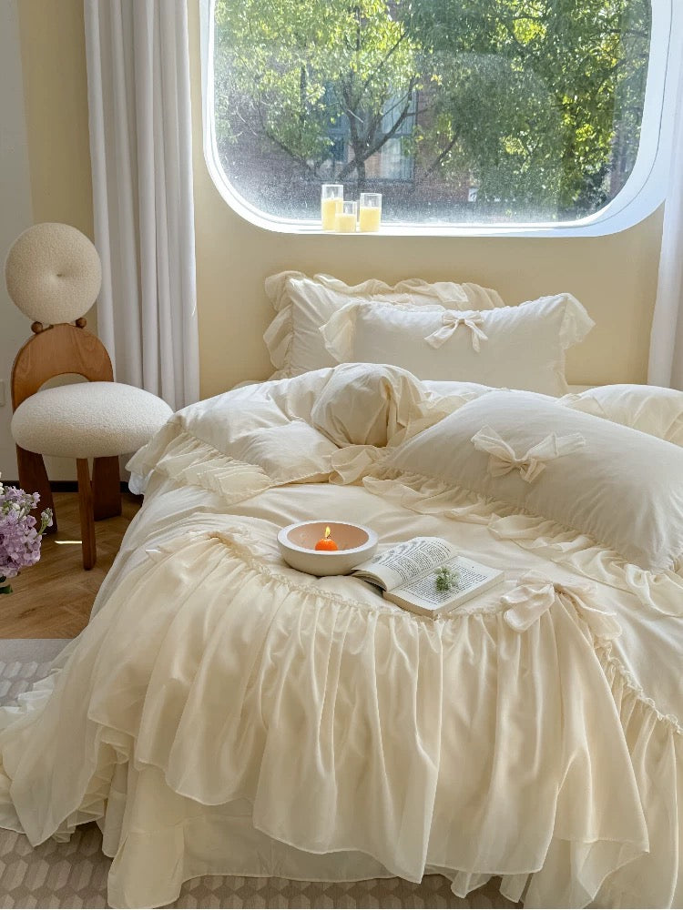 Neatly made bed with white bedding in a room with a window view of greenery.